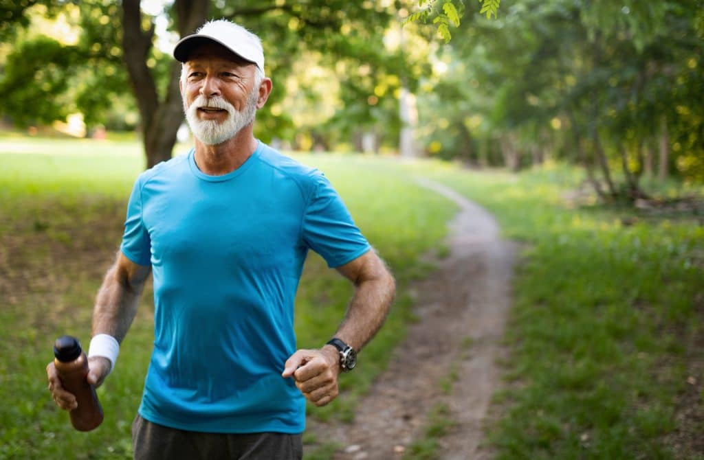 Older man jogging in a sunny park, reflecting active living supported by Strive Physiotherapy in Calgary